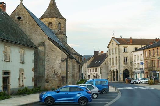 Bourg-Lastic, France - April 27, 2023: A road lined with houses and parked cars in a French town.