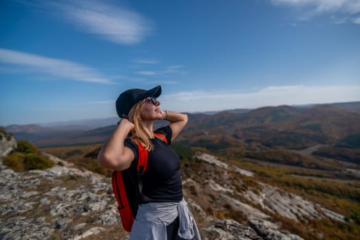 woman backpack on mountain peak looking in beautiful mountain valley in autumn. Landscape with sporty young woman, blu sky in fall. Hiking. Nature.