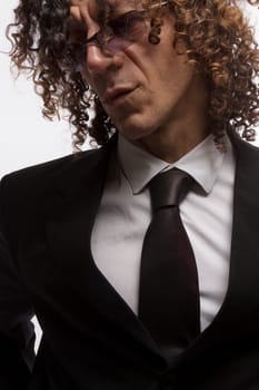 Cropped portrait of mediterranean looking man with curly hair wearing business suit and sun glasses