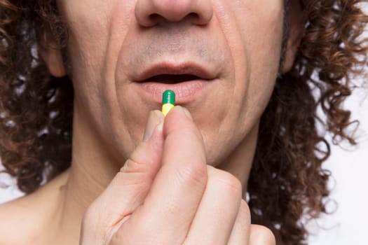 Cropped portrait of mediterranean looking man taking medicine pill