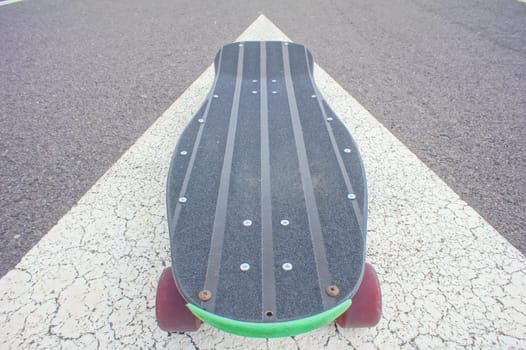 Vintage Style Longboard Black Skateboard on an Empty Asphalt Desert Road