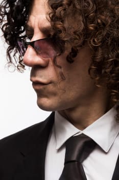 Cropped portrait of mediterranean looking man with curly hair wearing business suit and sun glasses