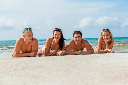 Group of laughing young people on the beach in summer holiday leisure lifestyle