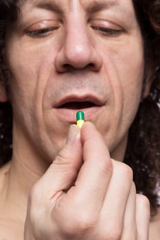 Cropped portrait of mediterranean looking man taking medicine pill