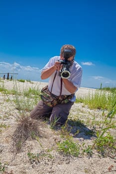 Biologist photographing plants in the sand dunes of Vadu beach, Romania.