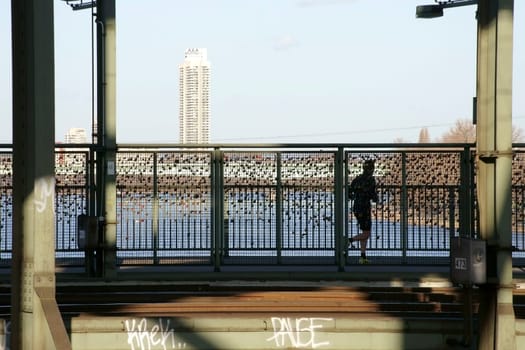 Cologne,Germany – February 02,2014: A jogger walks along a bridge crossing of the Hohenzollern Bridge over the Rhine River on February 2,2014 in Cologne.