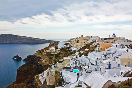Panorama view of the island of Santorini in Greece under cloudy sky..