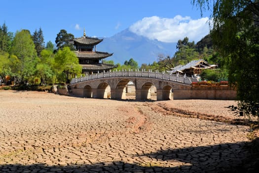 during a drought in China, cracks in the soil are showing in a river bed due to global warming