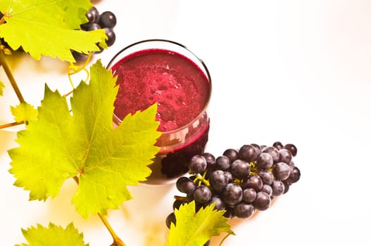 freshly squeezed red grape juice with vine leaves on a white background