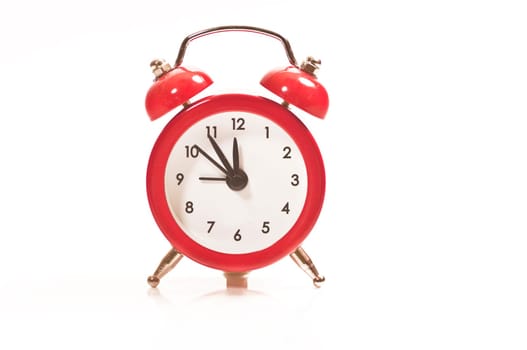 Red alarm clock on 5 to 12 on white background
