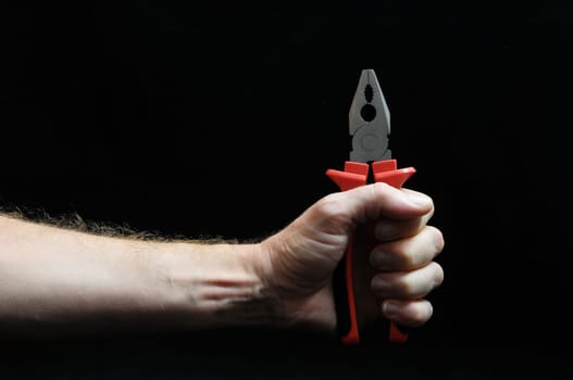 Pliers and a Hand on Black Background