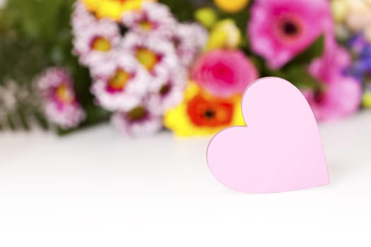 Pink heart with text space in front of a bouquet of flowers