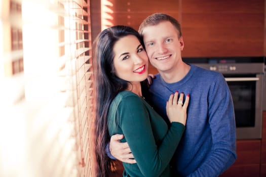 Young married couple in their house near the window louvers
