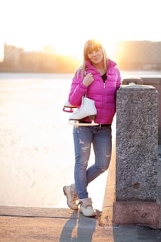 Beautiful young blond woman standing with her ice skates