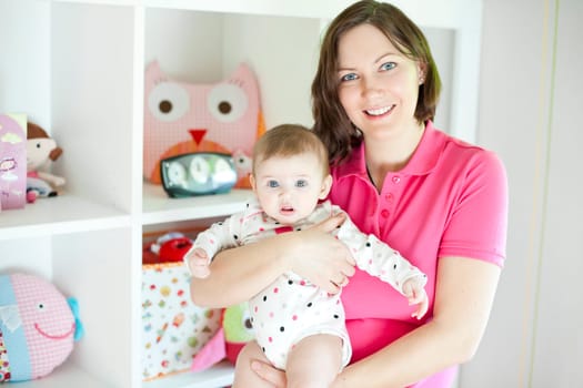 Mother with her dauther in a playroom with toys background