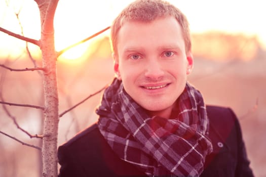 Young business man standing smiling in sunshine outdoors