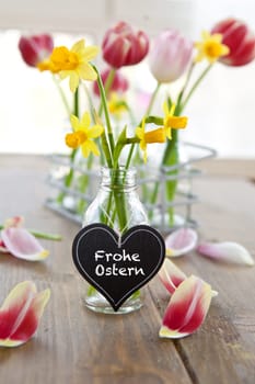 Fresh yellow daffodils in a small bottle with heart-shaped table