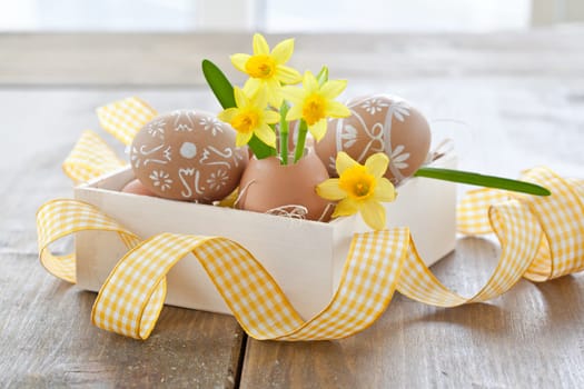 Fresh daffodils in eggshell and painted Easter eggs