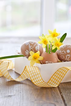 Fresh daffodils in eggshell and painted Easter eggs