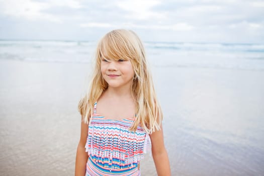 Portrait of cute young girl in swimming suit at the beach with ocean in background