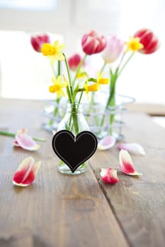 Fresh yellow daffodils in a small bottle with heart-shaped table