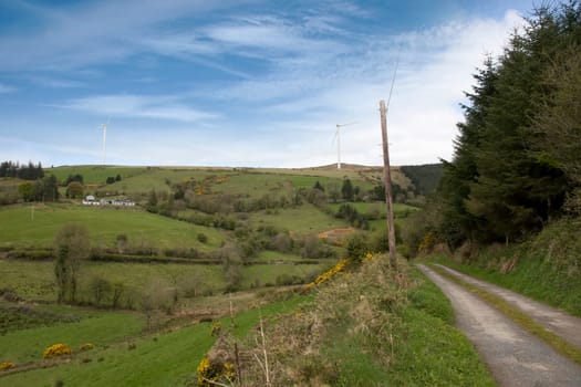 country lane in the irish countryside leading to a hill with windmills