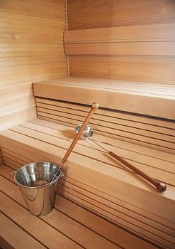 Bucket and scoop in wooden finnish sauna background.