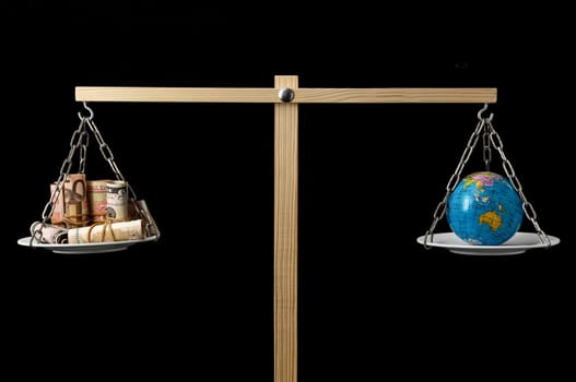 Globe Planet Earth and Money on a Two Pan Balance