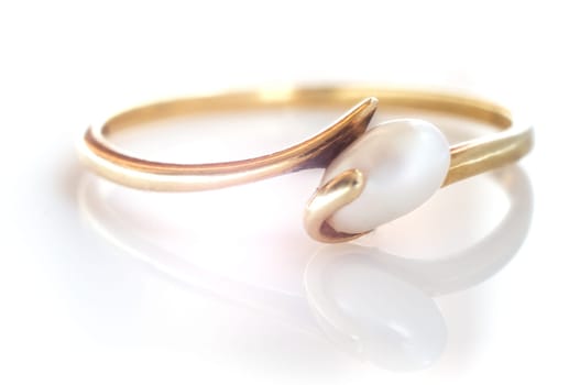 Macro shot of a golden pearl ring on a white background - with reflection.