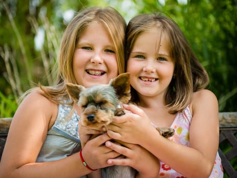 Happy smiling children playing with their pet - outdoor in backyard