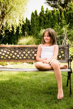 Daydreaming child portrait - little girl sitting on bench outdoor in backyard