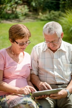 Lifestyle portrait of smiling happy senior couple working with tablet - outdoor