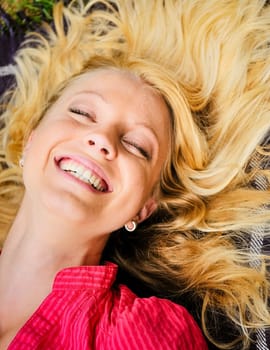 Portrait of young blond woman lying on rug and laughing  very much