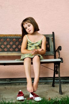 Sad girl - outdoor portrait of small cute child sitting on bench