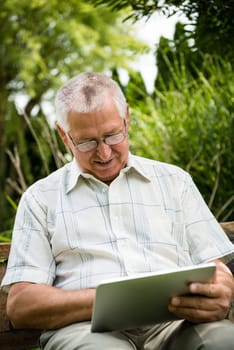 Lifestyle portrait of smiling happy senior man working with tablet