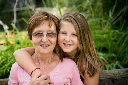 Outdoor lifestyle portrait of grandchild embracing grandmother