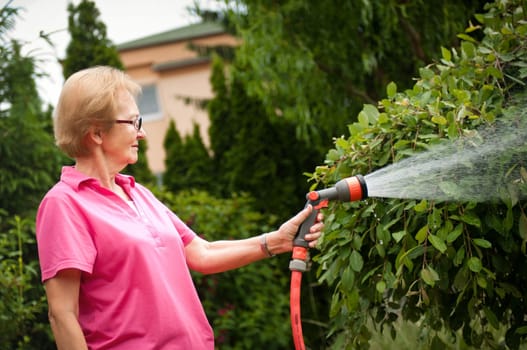 Senior woman watering garden
