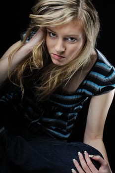 Young beautiful blond depressed woman (teenager)isolated on black background