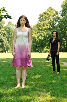 One girl is offended and her friend is calling for her - outdoors in park
