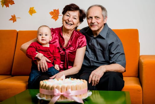 Grandparents with their small grandchild celebrating first birthday at home