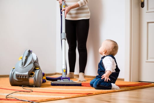 Cleaning up the room together - mother and her baby  with vacuum cleaner