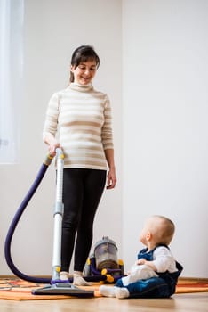 Cleaning up the room - mother and her baby  with vacuum cleaner