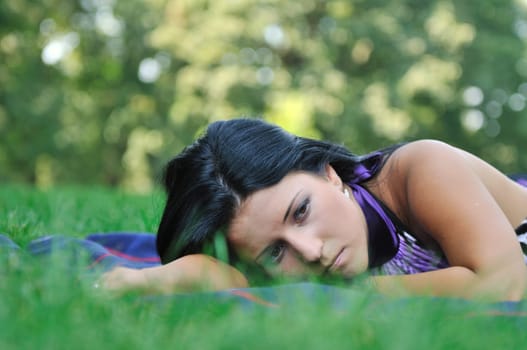 Young sad teenager lying outdoors in grass - detail