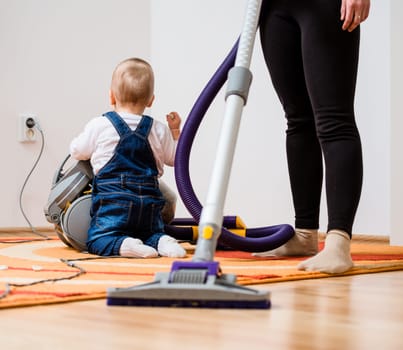 Cleaning up the room - mother and her baby  with vacuum cleaner