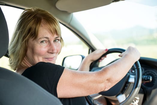 Lifestyle photo of attractive senior woman in car