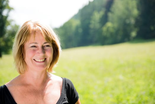 Portrait of happy smiling mature woman - outdoor in nature