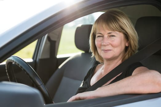 Portrait of attractive senior smiling woman sitting in car