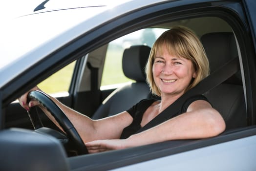 Portrait of attractive senior smiling woman sitting in car