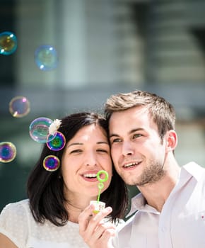 Young couple have great time together with bubble blower - outside in street