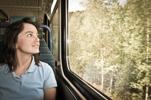 Young woman passanger sitting inside train and looking trough window